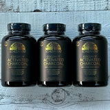 Three bottles of Schizandu Coconut Activated Charcoal on a wooden surface