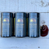 Three containers of Reishi mushroom powder on a wooden surface