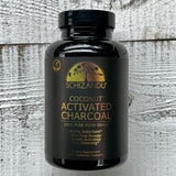 Black bottle of Schizandu Coconut Activated Charcoal on a wooden surface