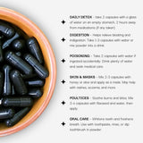 Bowl of black capsules with usage instructions on a white background
