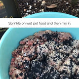 Pet food with black specks sprinkled on top, text overlay 'Sprinkle on wet pet food and then mix in.'