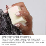 Hand holding a bar of soap with text about its safety for all hair types and pets.