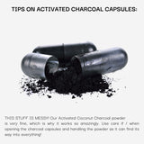 Activated charcoal capsules with powder spilling out on a white background