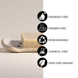 Bar of soap on a soap dish with certification icons for fragrance-free, paraben-free, biodegradable, chemical-free, and 100% pure organic on a light background.