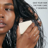 Person applying a product to their hair with text about hair care.