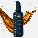 Bottle of Schizanu Undiluted Black Cumin Seed Oil with oil splashes on a white background