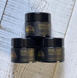 Three jars of Shilajit on a wooden surface