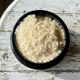 A close-up top-down view of Tocos/ Vitamin E in Miron glass jar, placed on a distressed white wooden surface.
