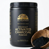 Black container of Schizandu coconut activated charcoal powder with a scoop of powder beside it on a white background.