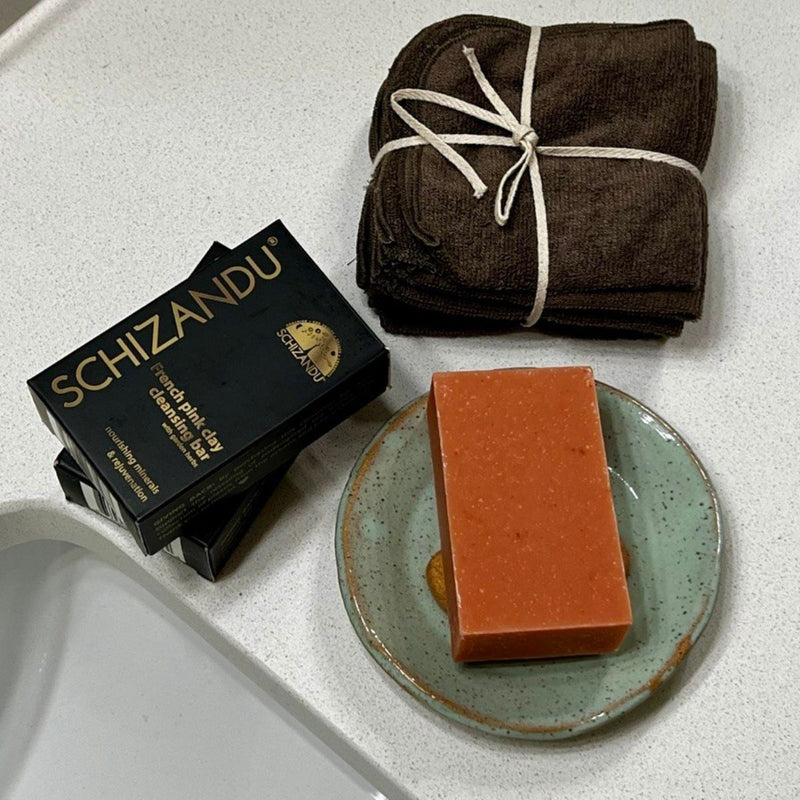 Bar of soap on a plate with Schizandu packaging and folded towels on a white surface