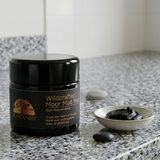 Schizandu Wildcrafted Moor Mud Mask jar on a marble surface with a small bowl of mud.