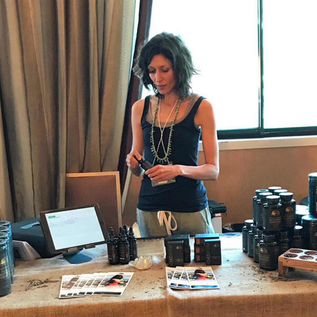 The Schizandu Founder at a table with various Schizandu products, including a computer and bottles.