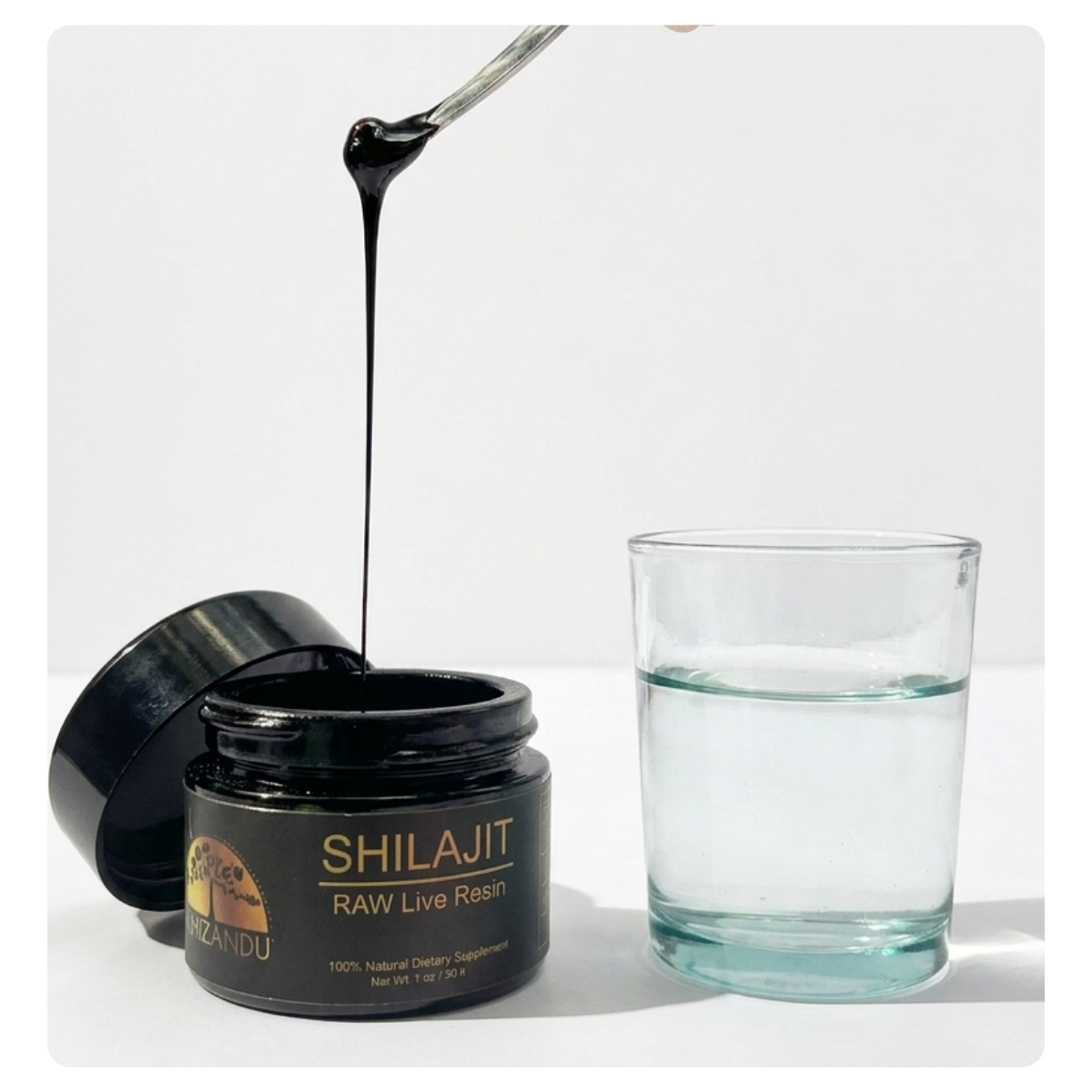A jar of Shilajit RAW Live Resin with its lid off, showing a spoon dripping thick black resin above a glass of water, on a white background.