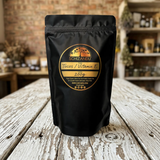 A black stand-up pouch of Schizandu Tocos / Vitamin E 200g, set on a rustic, weathered wooden table with a blurred brick wall and shelves in the background.